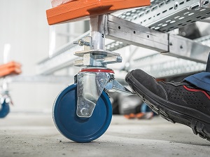 A workers boot locking the wheels on a mobile scaffold.