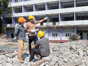 Structural engineers standing outside an old building discussing the demolition amongst the rubble.