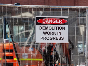 A danger sign on a fence outside a demolition project that says, "Danger, Demolition Work in Progress."