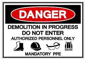 A danger sign that says, "Demolition in Progress, Do Not Enter, Authorized Personnel Only, Mandatory PPE" with images of safety boots, a hard hat, safety glasses, and a safety vest.o