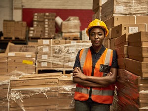 A warehouse worker standing in front of stacks of boxes.