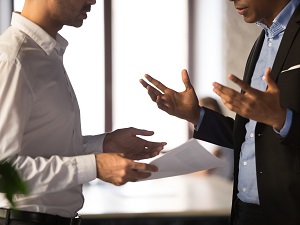 Two office workers, faces not shown, in a heated discussion.