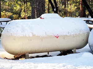 A large, above-ground propane tank covered in snow.
