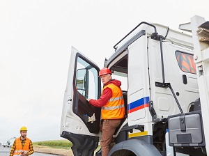 A truck driver stepping into the cab of his truck.