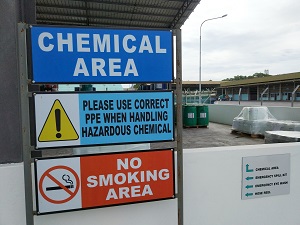A sign outside an industrial work space that says "Chemical Area" with a no smoking sign attached.