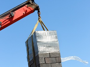 Crane lifting a load of masonry blocks.