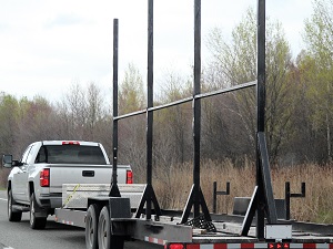 White pick-up truck towing a trailer loaded with materials.