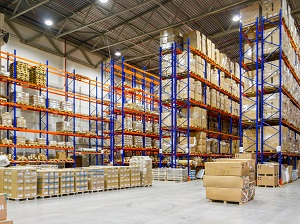 Boxes and materials stacked on steel racking inside a large warehouse.