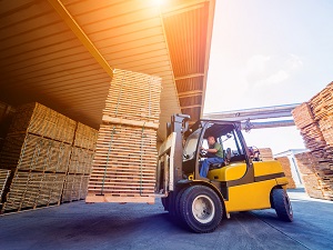 A forklift operator transporting pallets on a forklift on a loading dock.