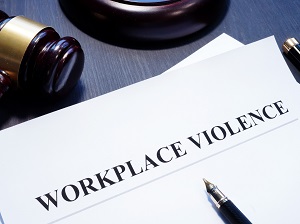 A courtroom gavel with papers on the desk that say Workplace Violence.