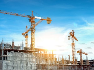 Multiple cranes on a large construction site with overhead power lines visible in the area.