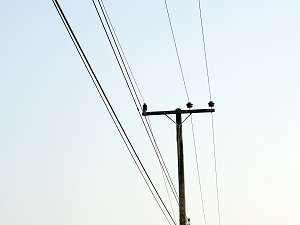 Overhead power lines against a blue sky.