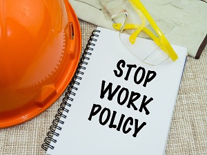 A general safety image showing a hard hat, safety glasses, work gloves and a spiral-bound notebook that is titled "Stop Work Policy."