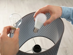 A person changing the lightbulb in a lamp.