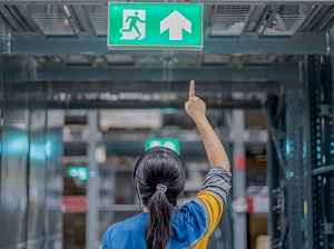 A worker pointing to the exit sign in a building.