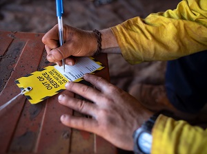 A worker filling out an out of service tag to place on electrical equipment that is defective.