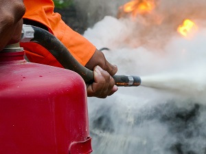 A worker using a fire extinguisher to put out a fire.