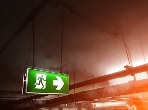 An exit sign pointing the way in a building where there is a fire.