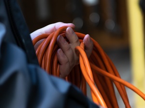 Worker rolling up an orange extension cord.