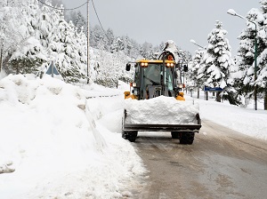 Front loader moving snow off of a road in winter weather.
