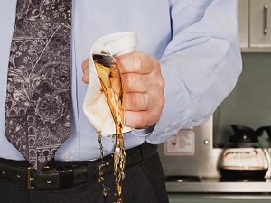 Office worker crushing a cup of coffee in anger so it spills.