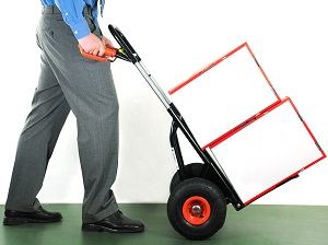 Male office worker pushing a hand truck with two boxes on it.