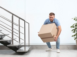 Man if office building lifting a box incorrectly and awkwardly.