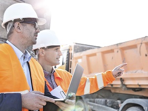 Two Construction Supervisors Wearing HVSA Near Heavy Equipment