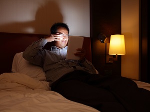 Man Rubbing Eyes, Looking at Tablet in Dark Bedroom
