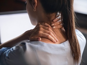 Woman Working on Computer But Massaging Neck Due to Discomfort