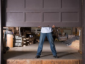 Worker Raising Industrial Garage Door to Warehouse