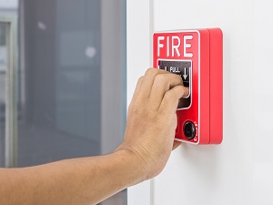 Person Pulling Fire Alarm in Building