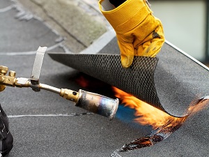 Roofer Using a Torch to Apply Shingles with Tar