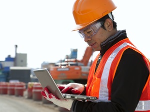 Construction Supervisor Wearing PPE on Laptop at Construction Site