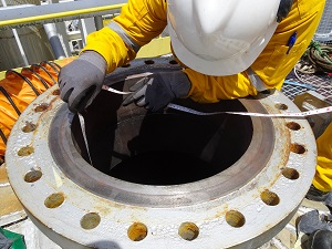 Worker Measuring Confined Space with Tape Measure