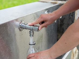 Person Refilling Water Bottle from Faucet