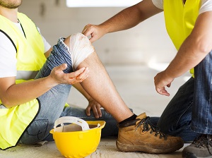 Worker Performing First Aid on Another Worker Who Hurt His Knee