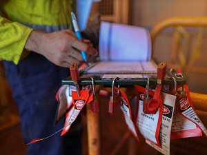Tags and Locks for Lockout Tagout, Worker Recording Notes in Notebook