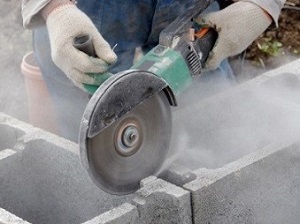 Gloved Hands Using Portable Grinder to Cut Sone