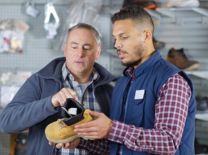Two men shopping for work boots in a store.