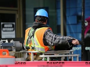 A worker wearing a hard hat, a safety vest and a personal fall arrest system in an aerial lift.