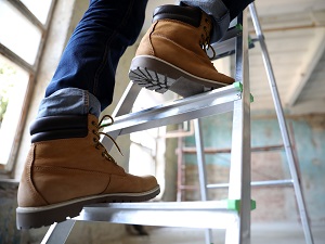 Worker climbing up a step ladder.