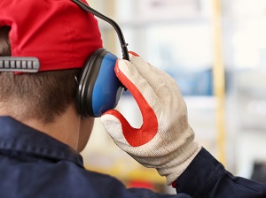 Worker wearing hearing protection and work gloves.
