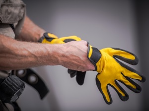 Worker putting on yellow and black work gloves.