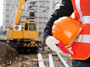 Worker Standing by Crane at Construction Site