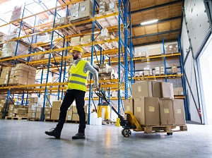 Warehouse worker pulling a loaded pallet jack.