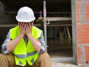 Construction worker with his head in his hands, like he's upset.