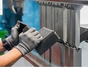 Operator using a press brake to form a metal part with segmented dies while keeping hands clear of the point of operation.