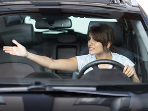 A woman driving in traffic is yelling at another driver.