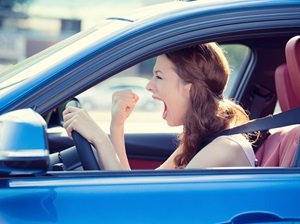A woman driving in traffic is very angry and she is yelling while driving.n